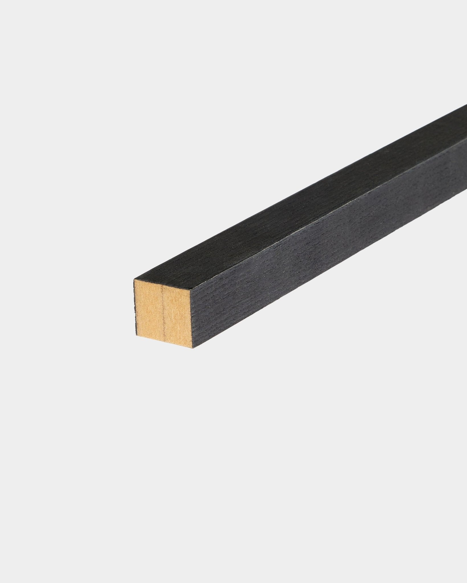 WoodUpp Black eindlamel in essen, 2,2 cm, ontworpen voor installatie met Akupanel Akoestisch paneel, liggend op een wit oppervlak met één onafgewerkte zijde.